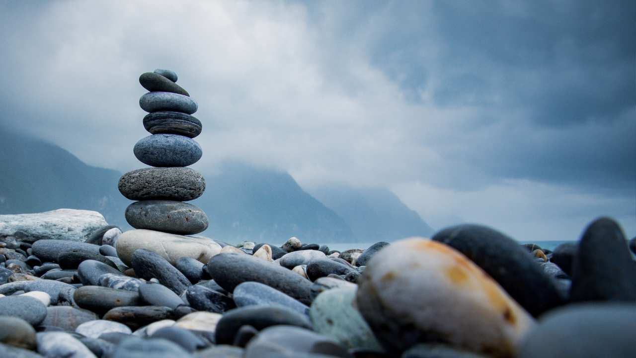 A tower of stones arises from scattered stones on the shore. 