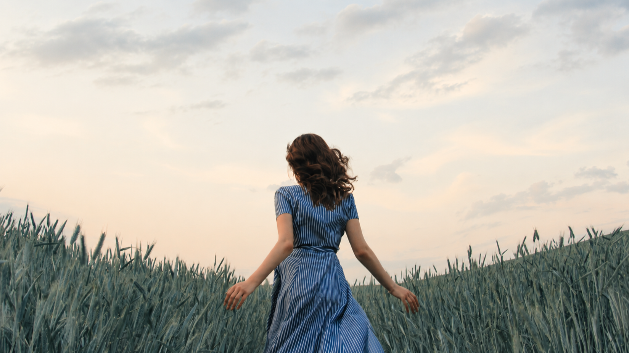 A woman moves through a grassy field. 