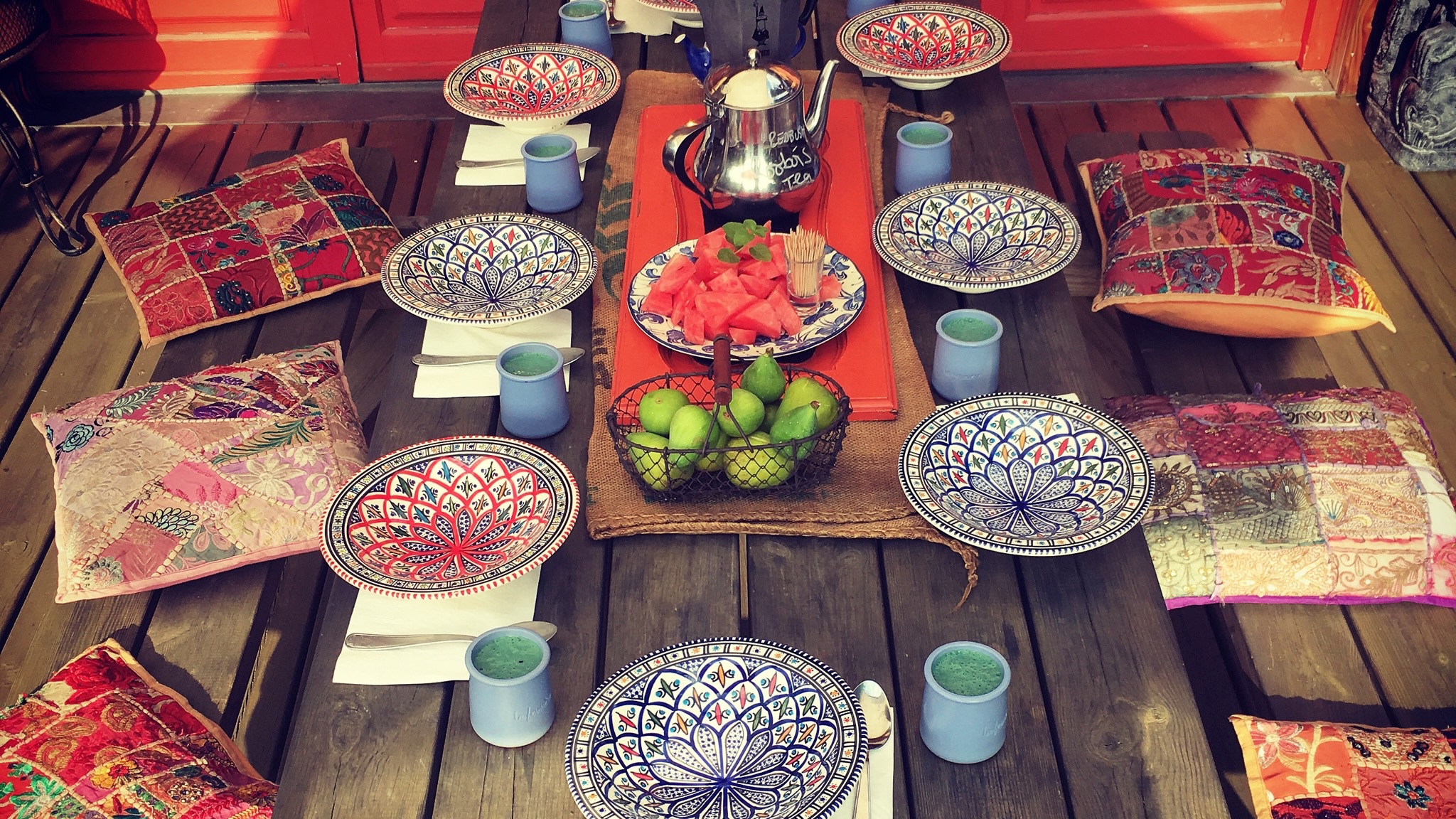 **Image alt text :** Table conviviale dressée avec des assiettes, des fruits et des coussins, évoquant une alimentation consciente et partagée dans l’esprit du yoga.