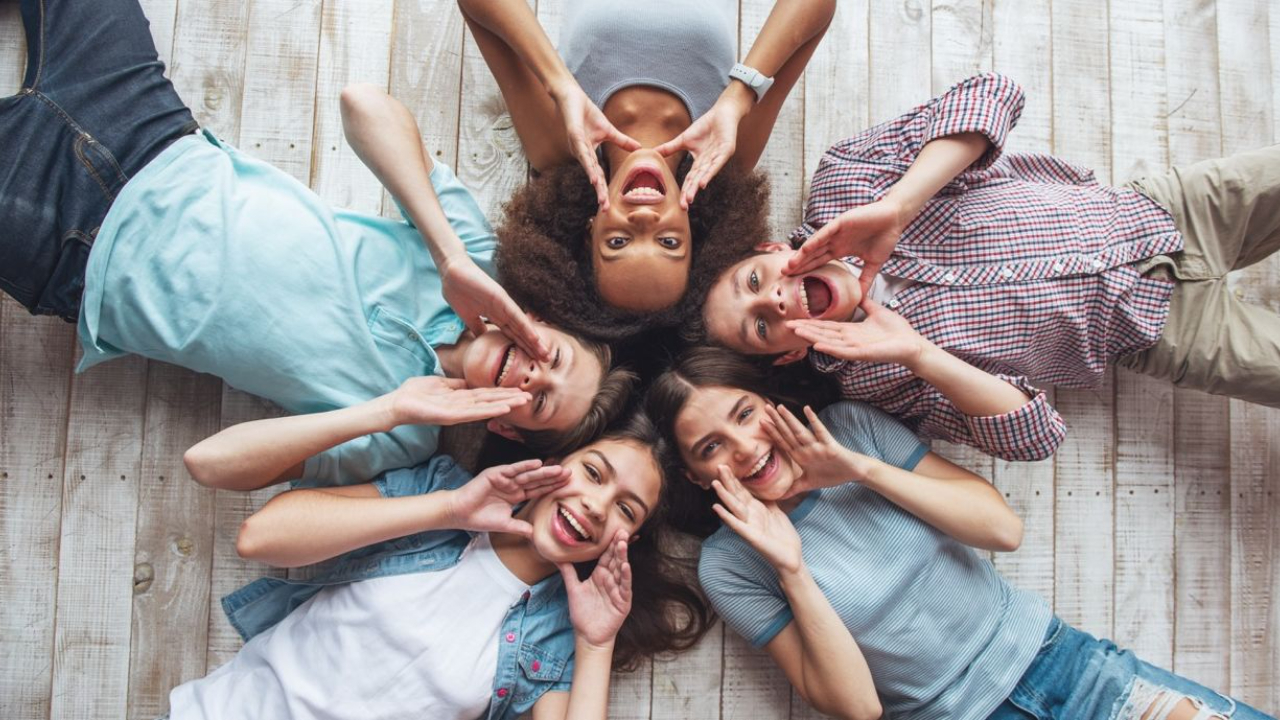 5 people as seen from above shouting a message and smiling