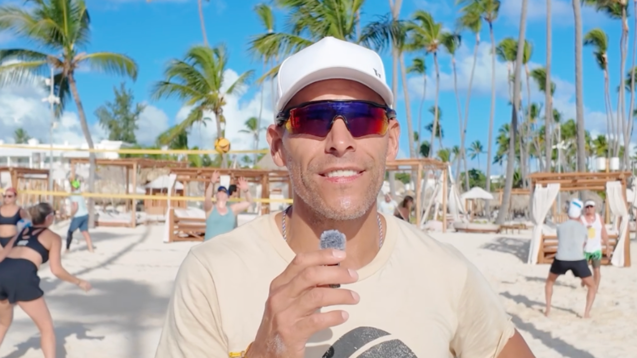 Coach at a Better at Beach adult beach volleyball camp with players training on beachside courts