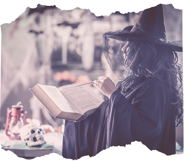 Woman in a witch hat reading an open book by candlelight