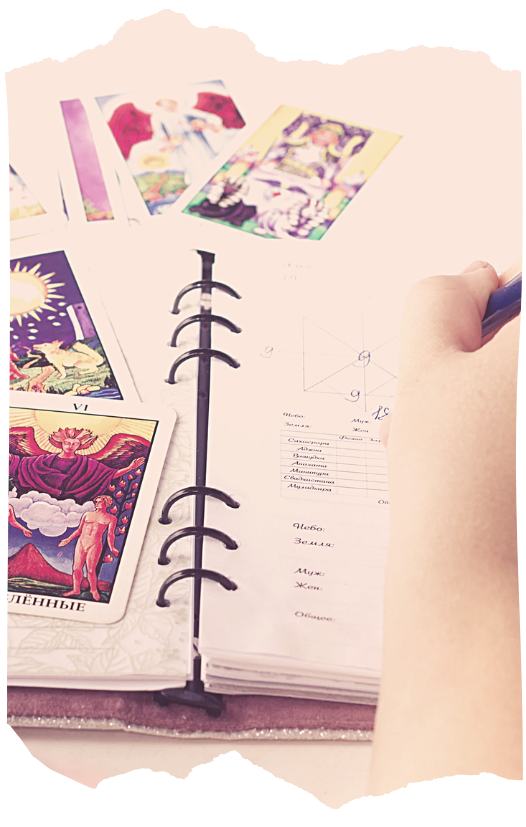 Tarot cards beside a handwritten journal for recording readings