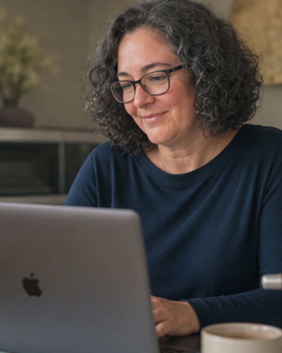 o-Anne Mac Millan, Kajabi website designer and mentor, working at her MacBook with a coffee nearby