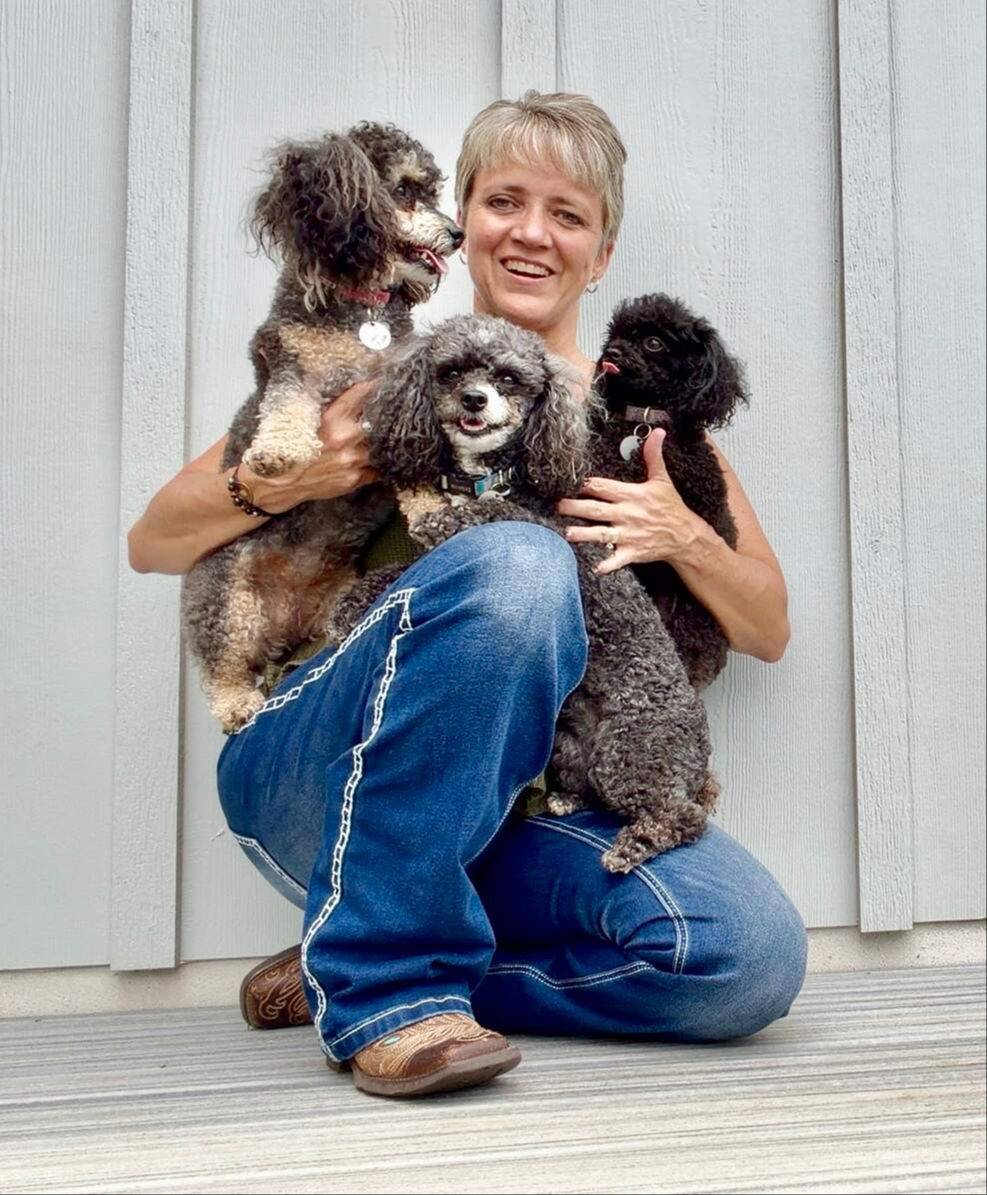 Dolly Denson smiling, holding her three poodles
