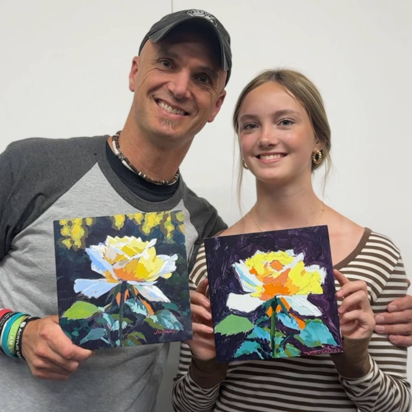 Willow and her dad Jed holding their Sunlit Rose paintings