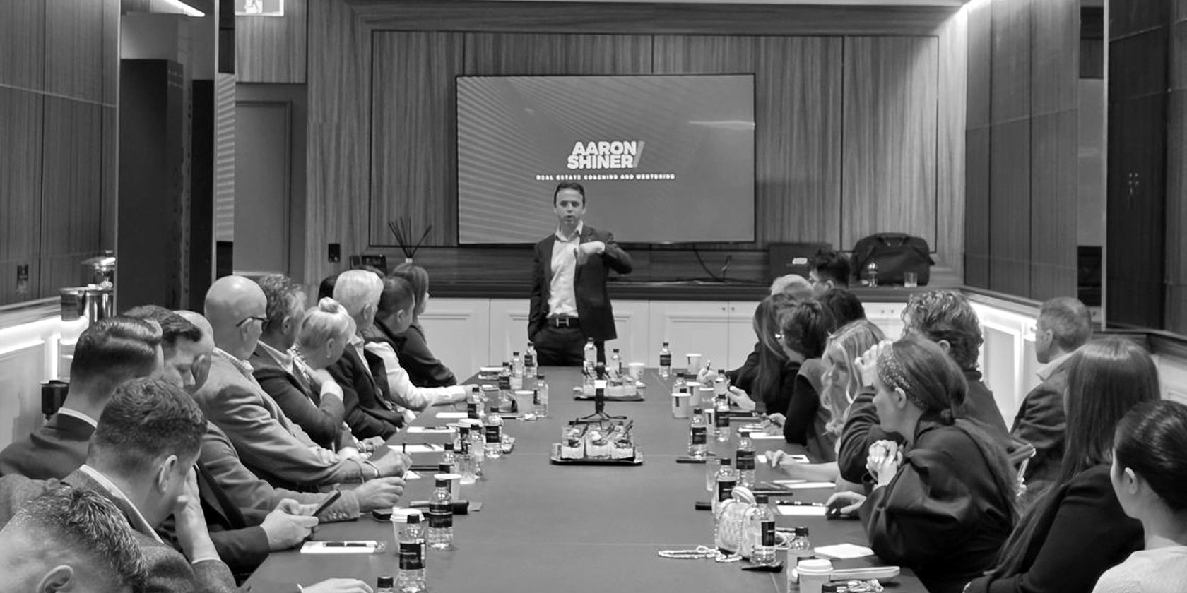 Aaron Shiner at the head of a long boardroom table, a full sales team either side
