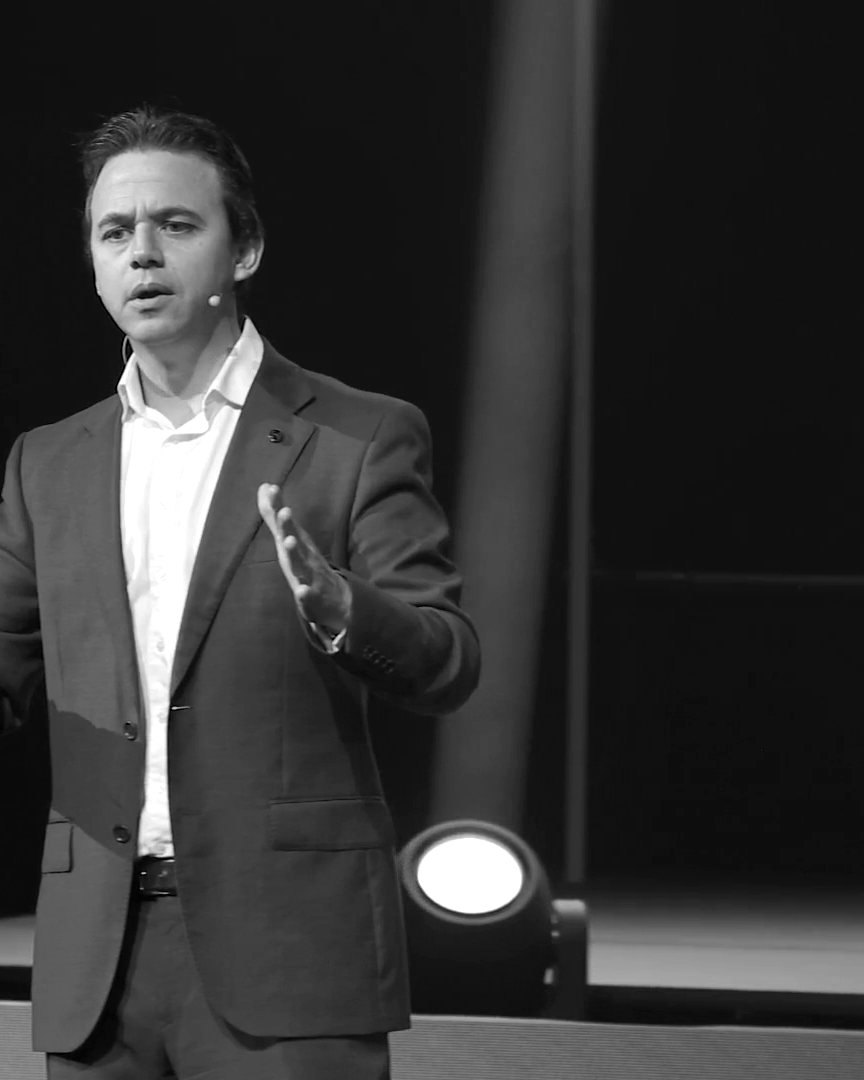 Aaron Shiner on stage at NZREC, both hands open, mid-sentence