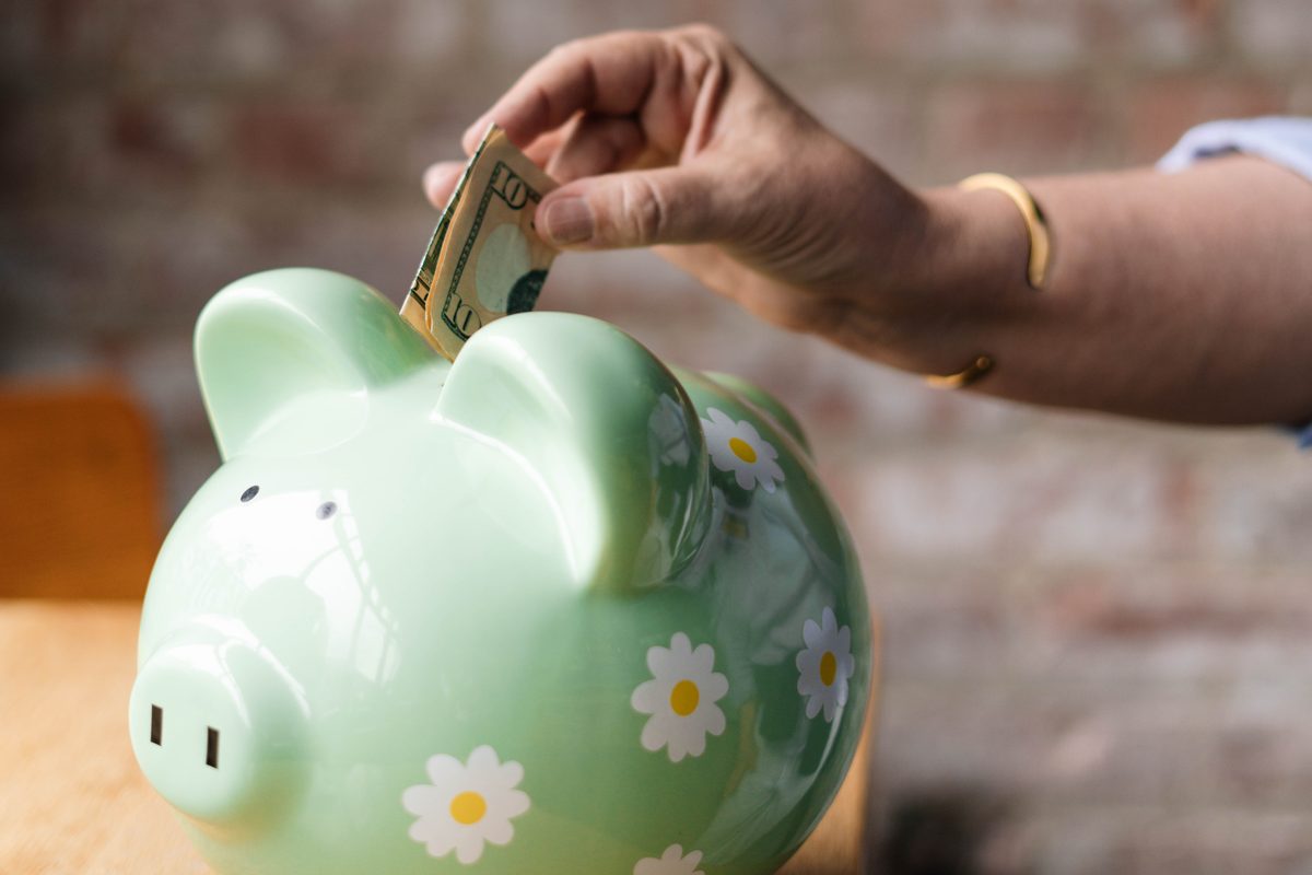 Money going into a green piggy bank