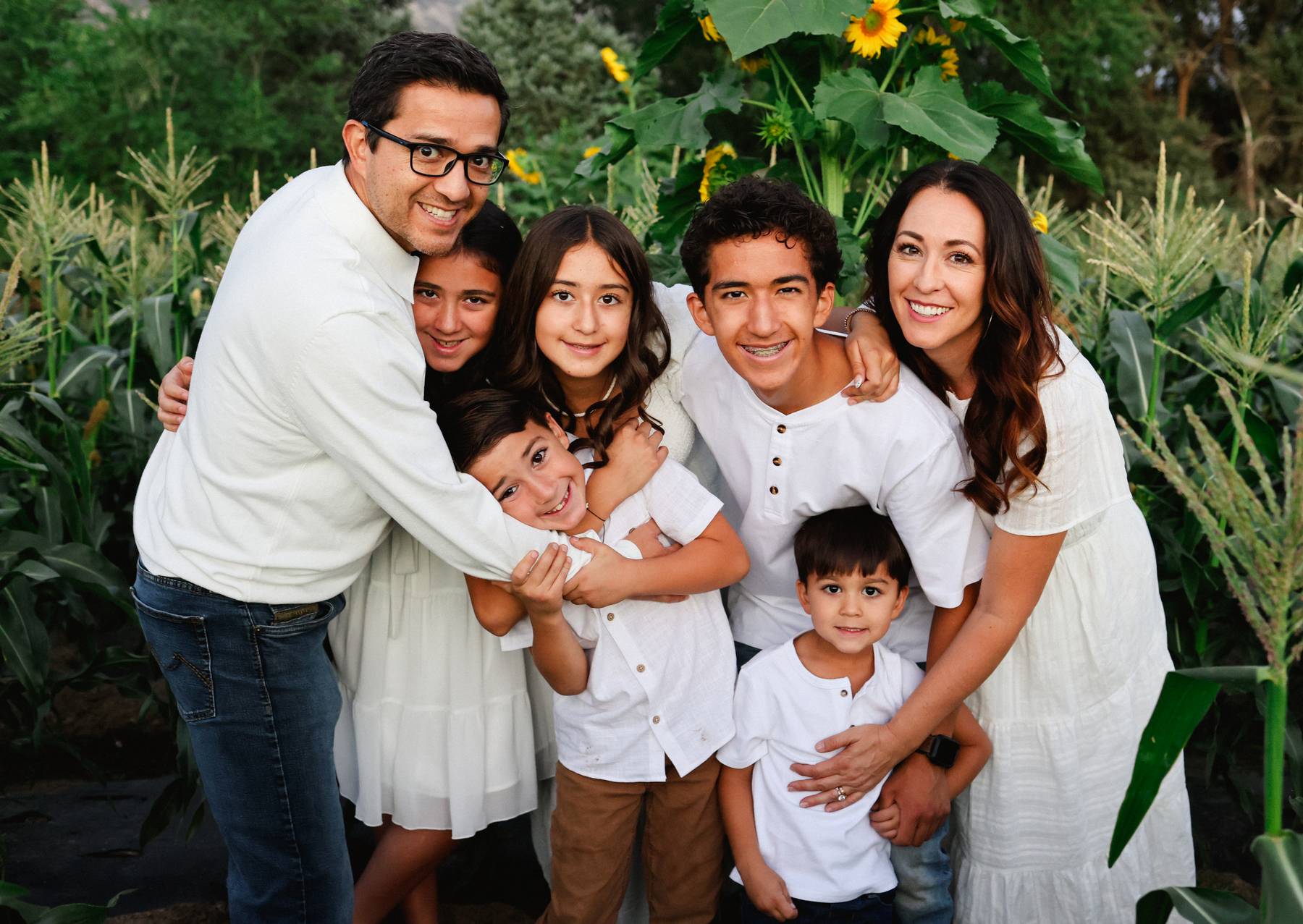 Maria and her family hugging and laughing in a field of sunflowers