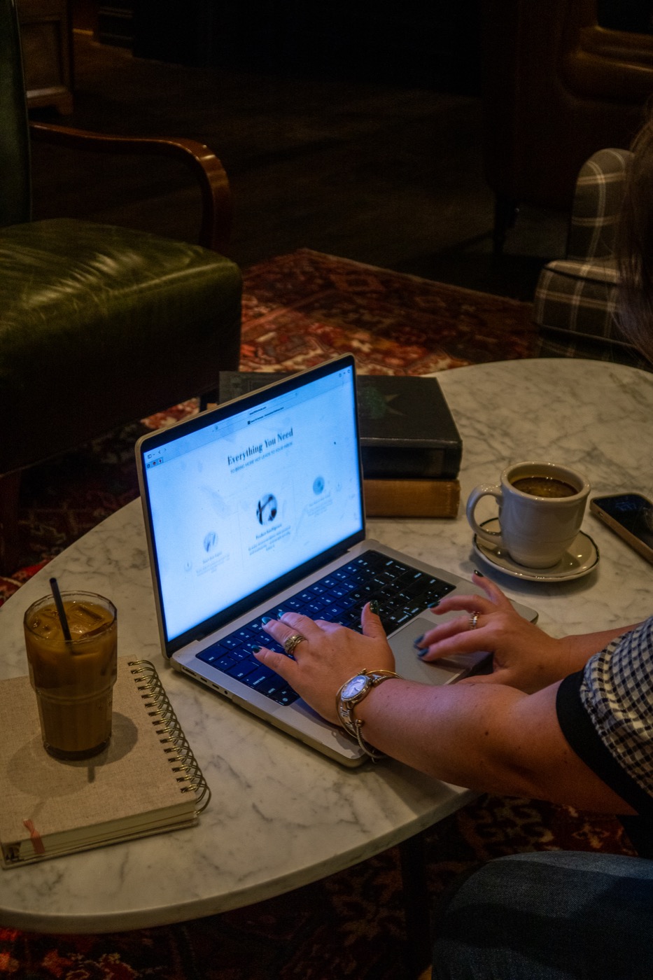 Hands typing on a laptop at a marble cafe table