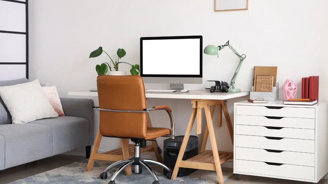 Home office workspace with desk, computer, chair, sofa, and storage cabinet used to illustrate business use of home