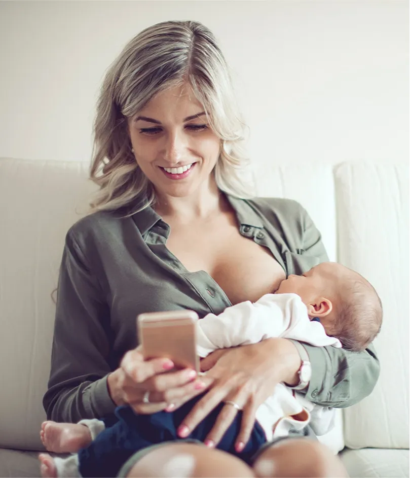 Women breastfeeding her baby whilst on mobile phone