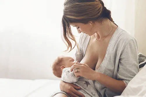 Women Breastfeeding Baby On Bed