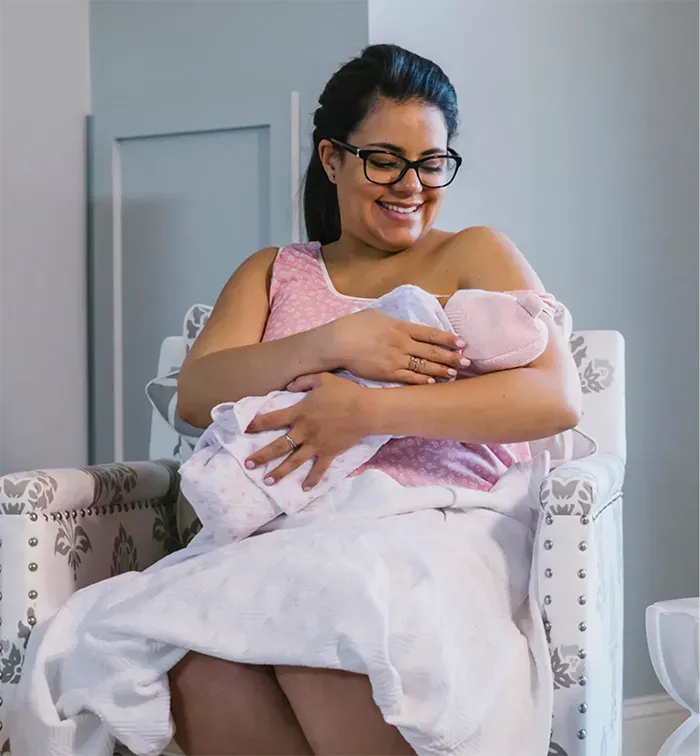 Hispanic woman breastfeeding on chair