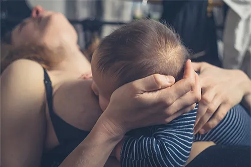 Mother breastfeeding in pain