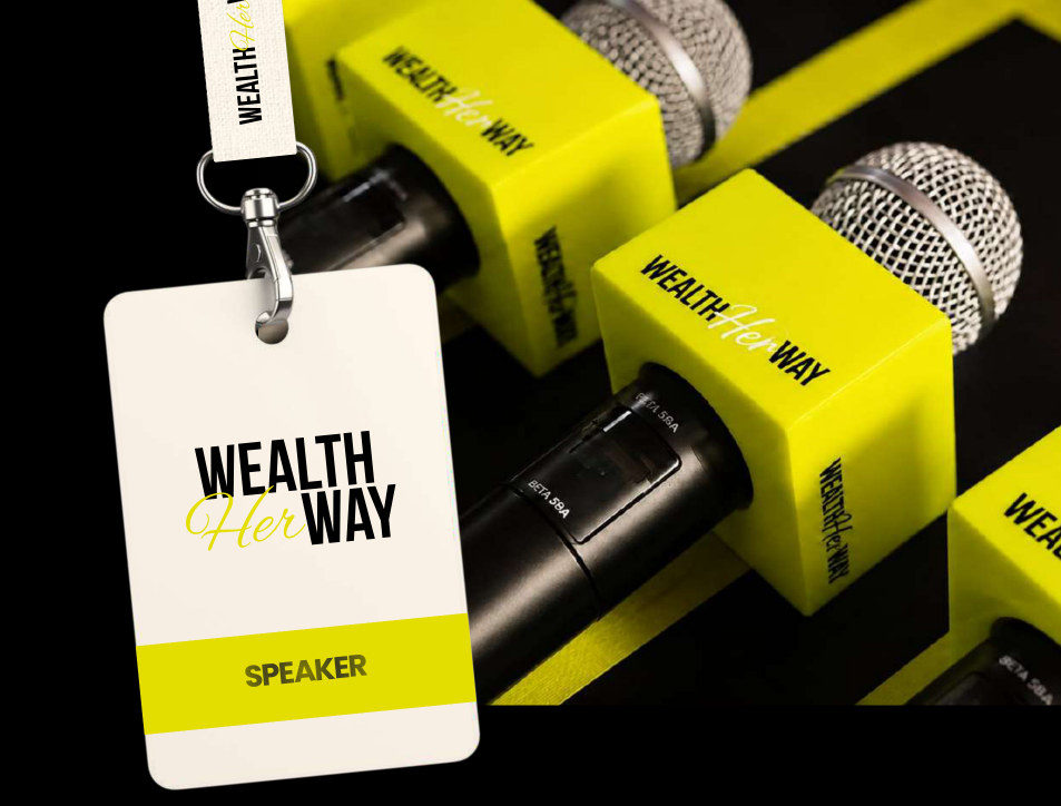 A cream Wealth Her Way SPEAKER badge on a lanyard hanging in front of yellow Wealth Her Way microphones.