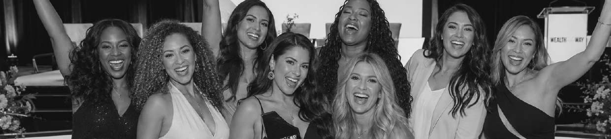 Black-and-white photograph of eight women celebrating together at a Wealth Her Way event.