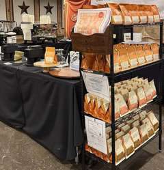 A vendor display stand filled with packaged goods beside a black-draped table.