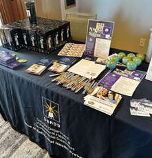 A navy-draped vendor table laid out with brochures and small products.