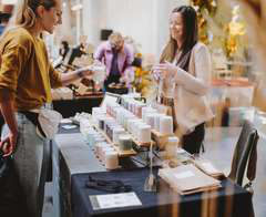 Shoppers looking over a vendor table of skincare products.