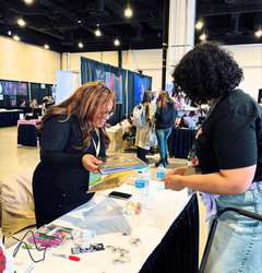 Attendees browsing a vendor table in a busy exhibition hall.