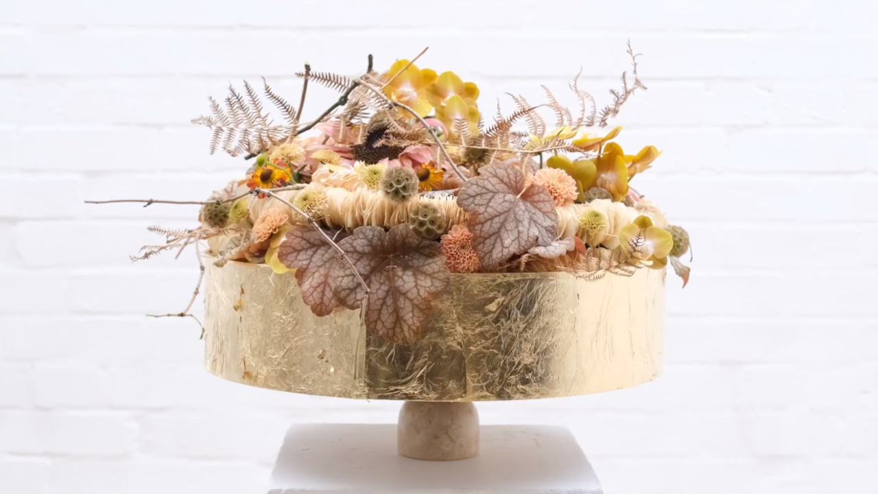 Joseph Massie’s October Gold floral arrangement with soft peach, gold and bronze flowers arranged in a gold lampshade framework.