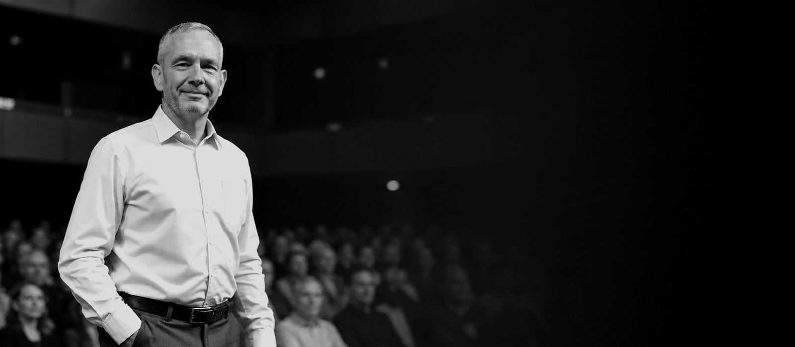 Dave Diggle on stage in front of a seated audience
