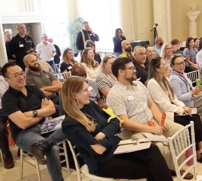 A room of smiling leaders seated during an offsite session