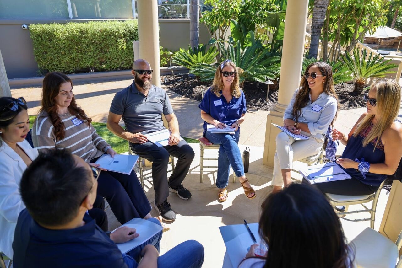 Leaders seated in a circle outdoors during a small-group discussion