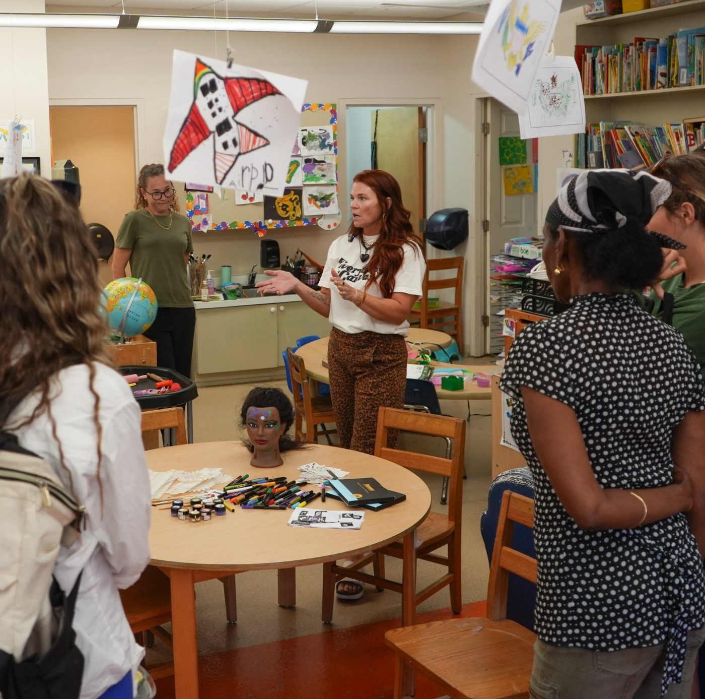 Kristen leading a training with a group of teachers in a preschool classroom