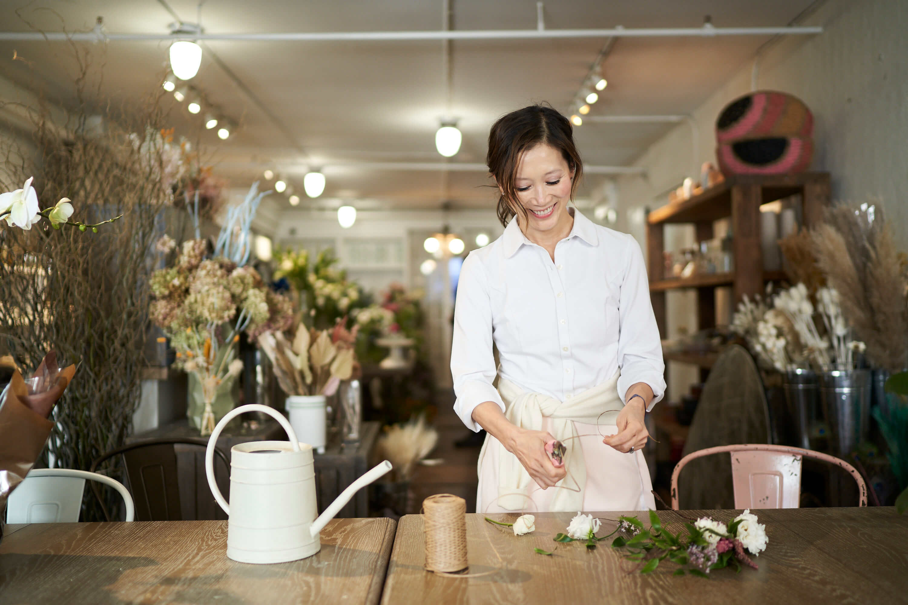 Sophia Ruan Gush&eacute;e arranging flowers at a wooden table