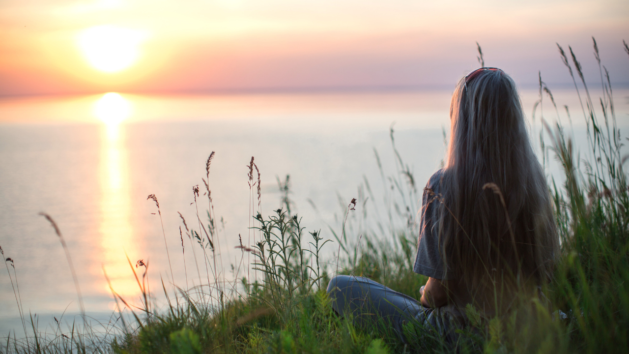 woman overlooking a lake watching the sunset and feeling calm