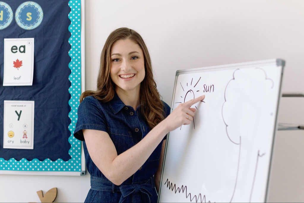 Alison Ryan sitting in a classroom with a white board and set of magnetic letters, placing the 