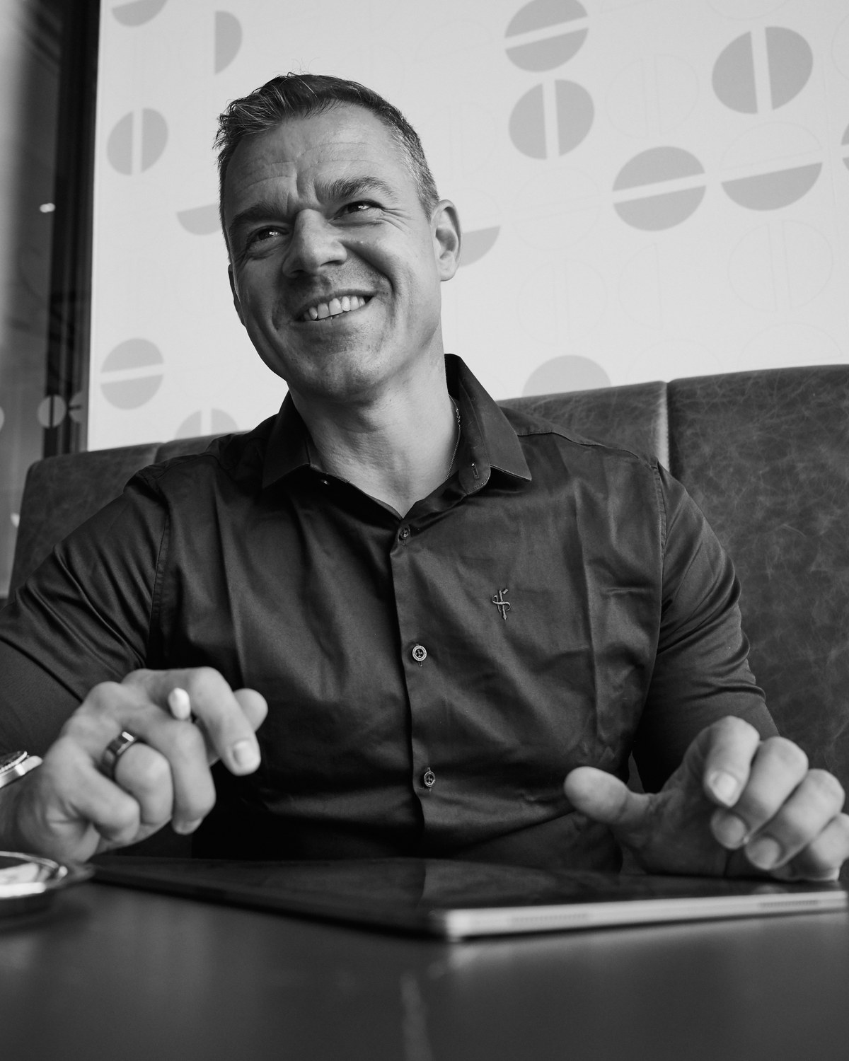 Alex Hurschler lacht im Café, Tablet und Stift auf dem Tisch