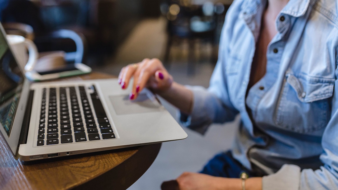 Woman in denim shirt working on laptop reviewing Meta ads campaign
