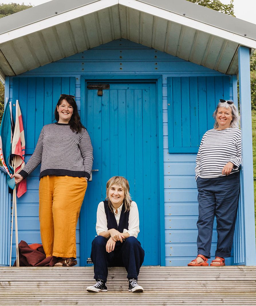 Katie Helen and Tania smiling outside a blue beach hut