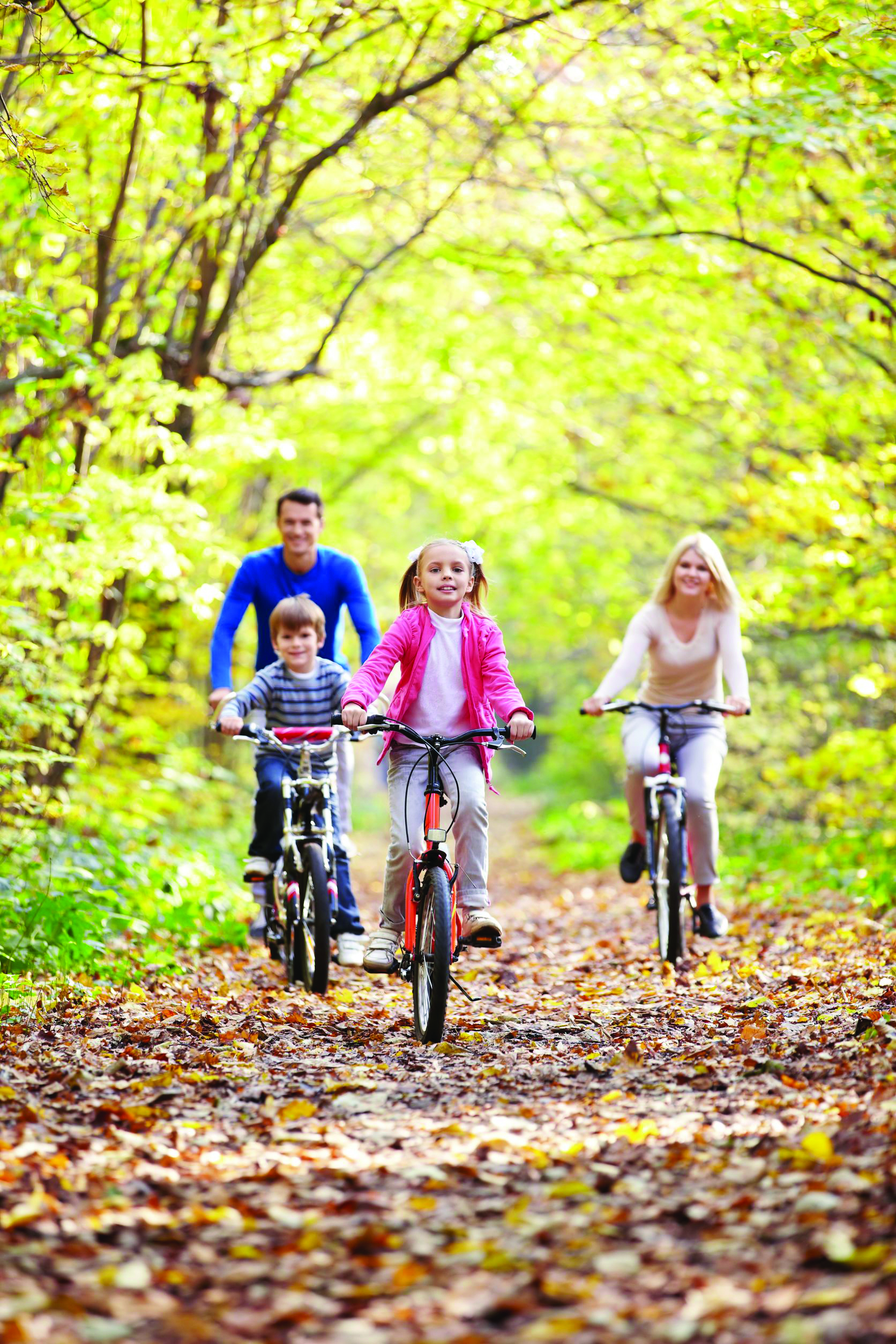 A family cycling together on a country lane in autumn