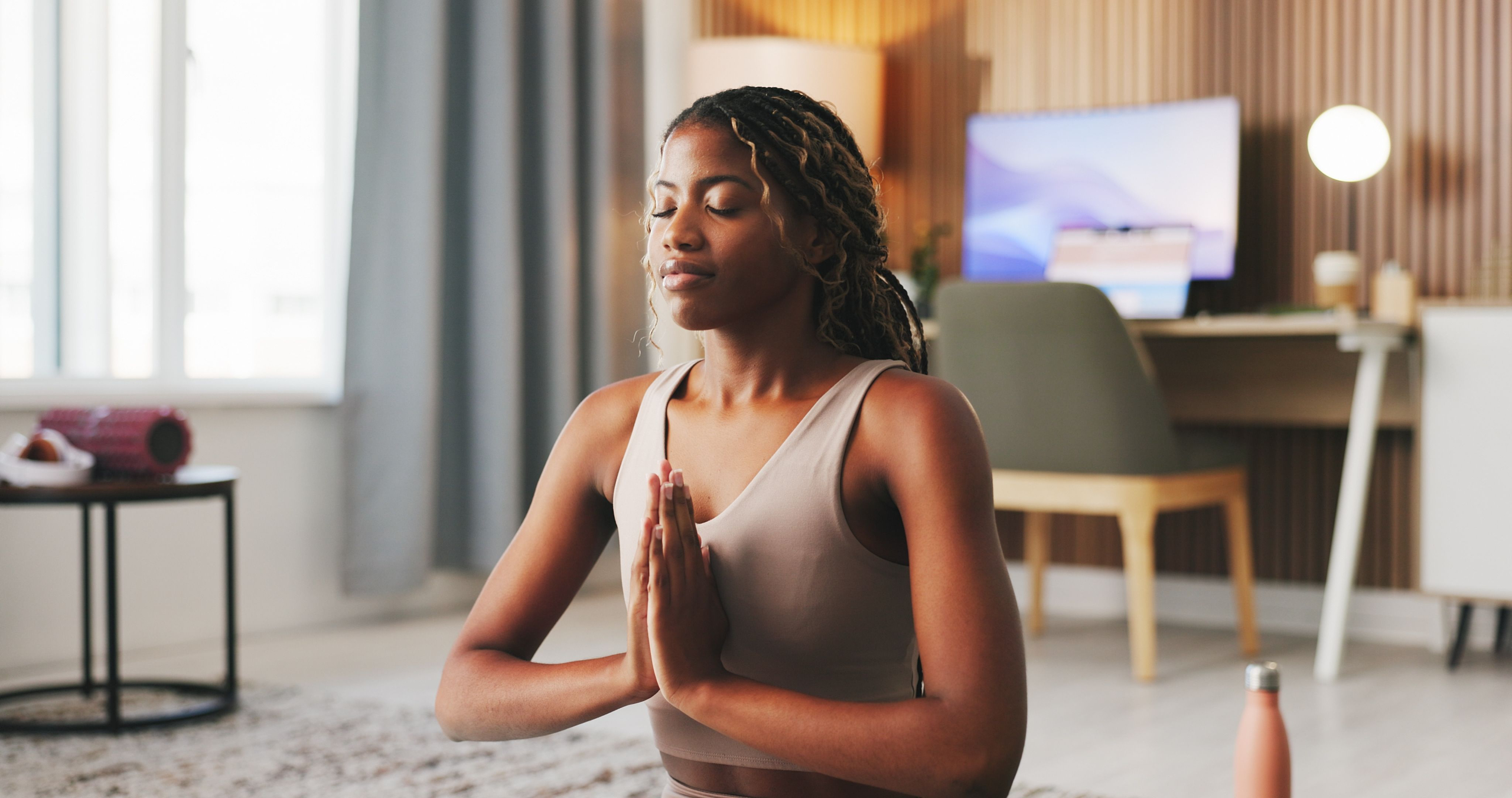A young woman in meditation, eyes closed and hands joined softly at her chest