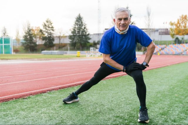 senior athlete stretching his hips