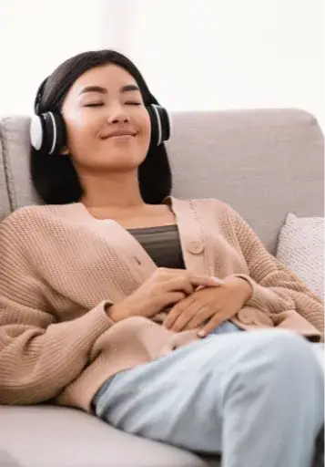 woman relaxing and sitting with eyes closed with headphones listening to guided experience