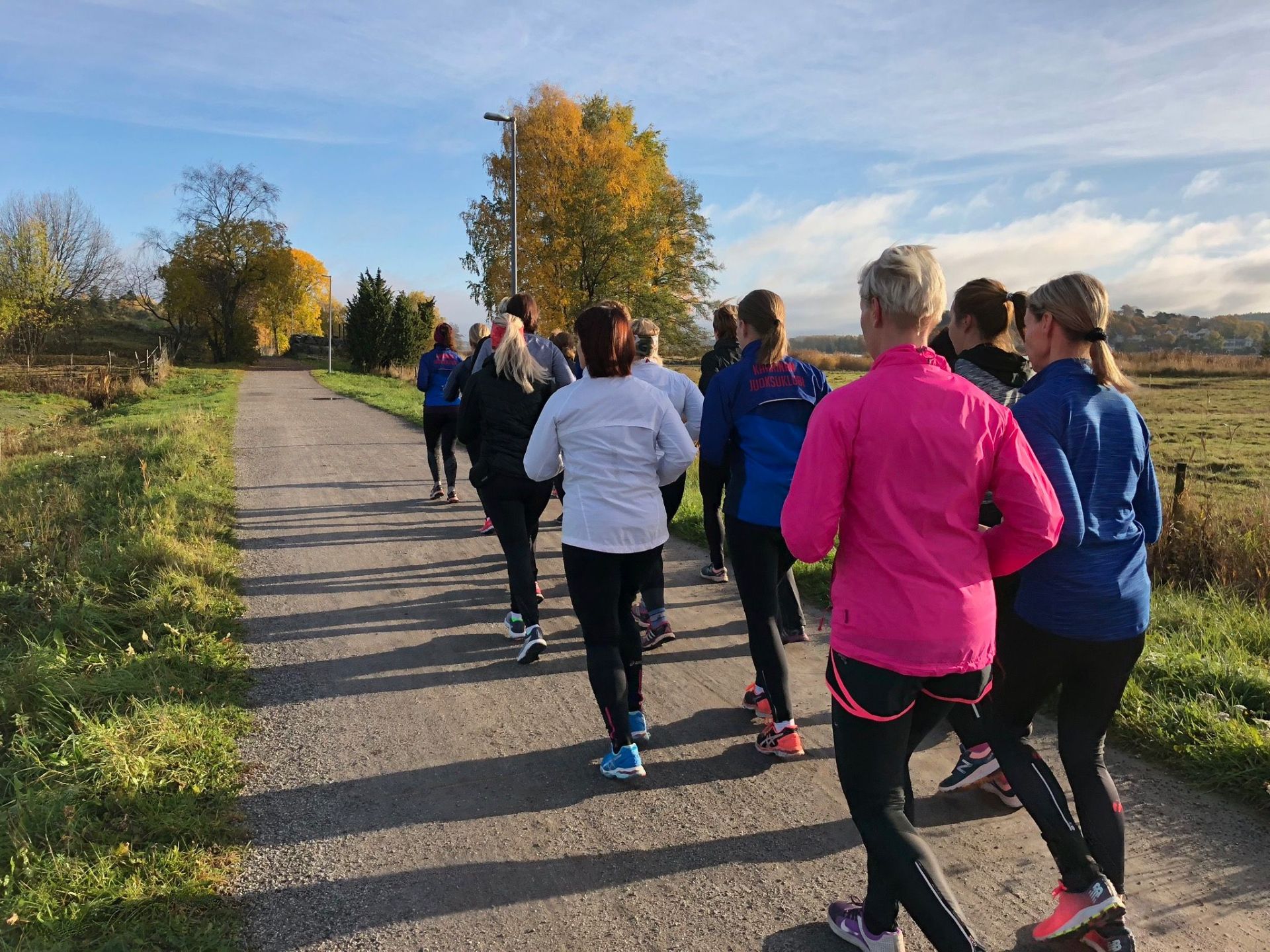 Juoksuklubi group running training on a countryside road in Finland