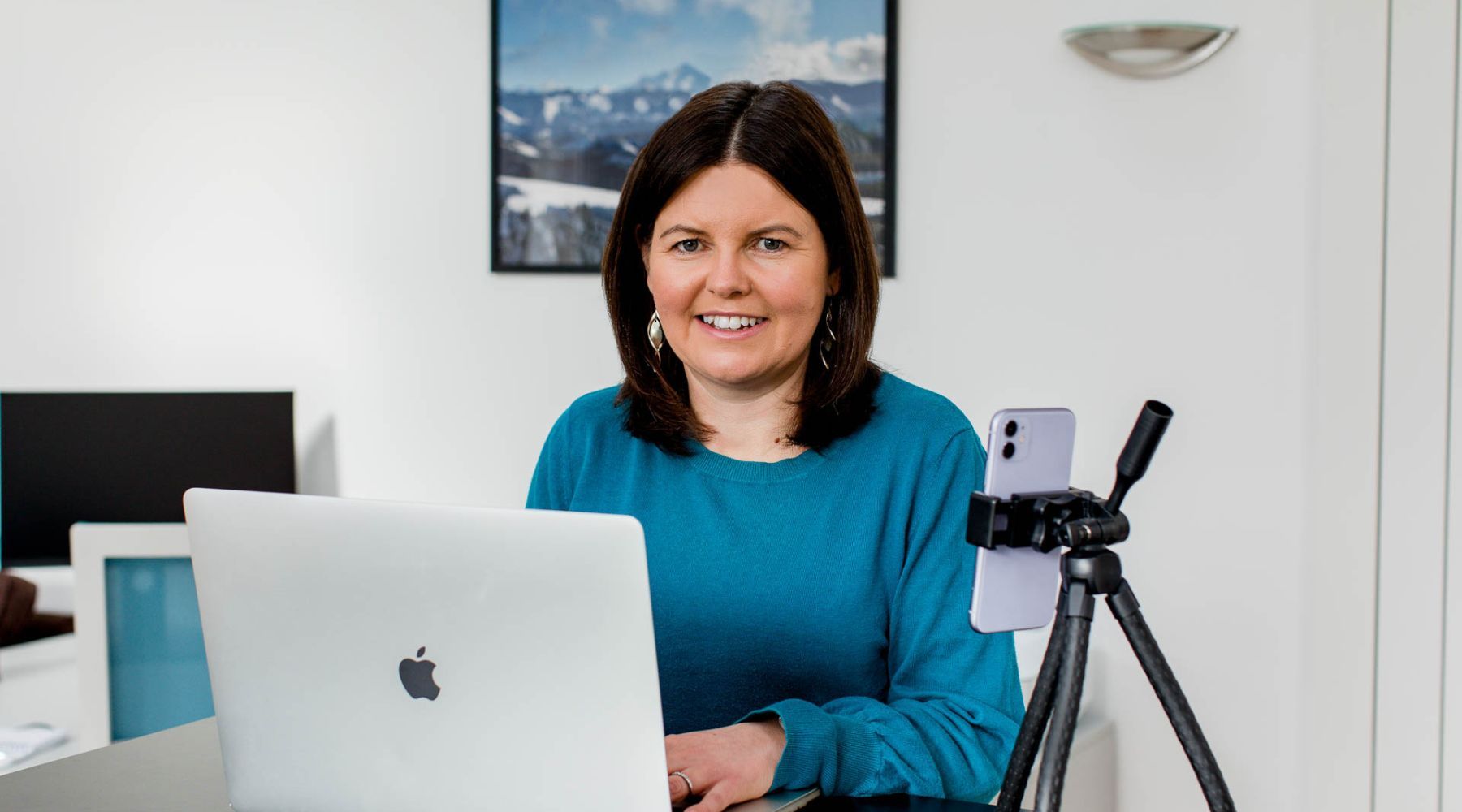 Personon lap top and phone with like icons coming out of the laptop