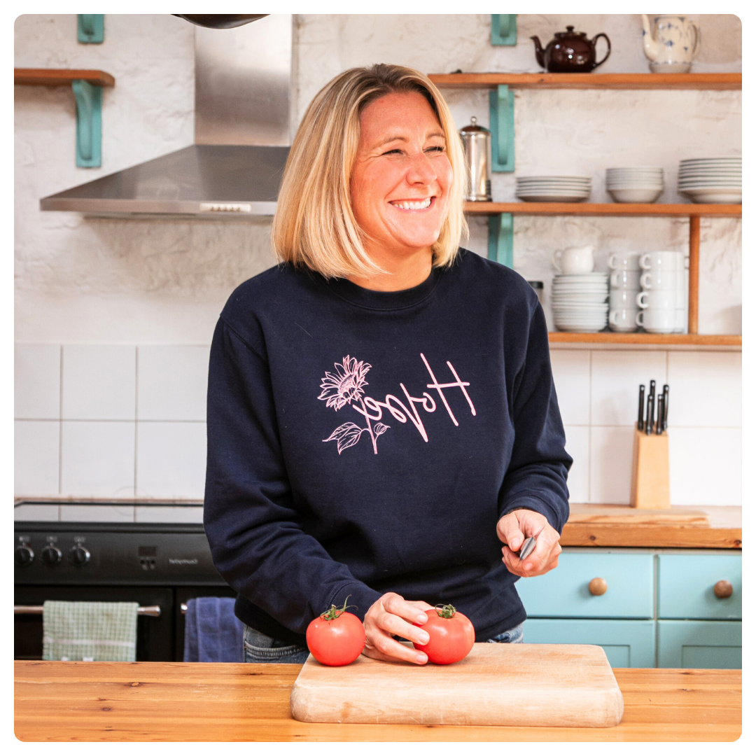 Karen Sutton sitting on a teal couch, wearing a yellow top, smiling while holding a yellow mug. The text below invites widows, widowers, and surviving partners to join a free Facebook support community.