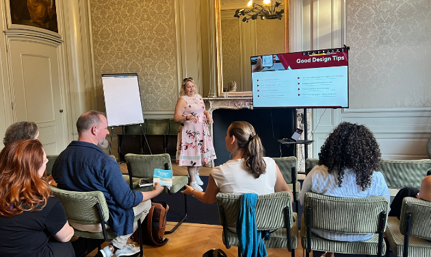 Coach Aga in a room providing a masterclass, with the screen visible and Aga next too the scree, and back of 5 participants sitting on chairs