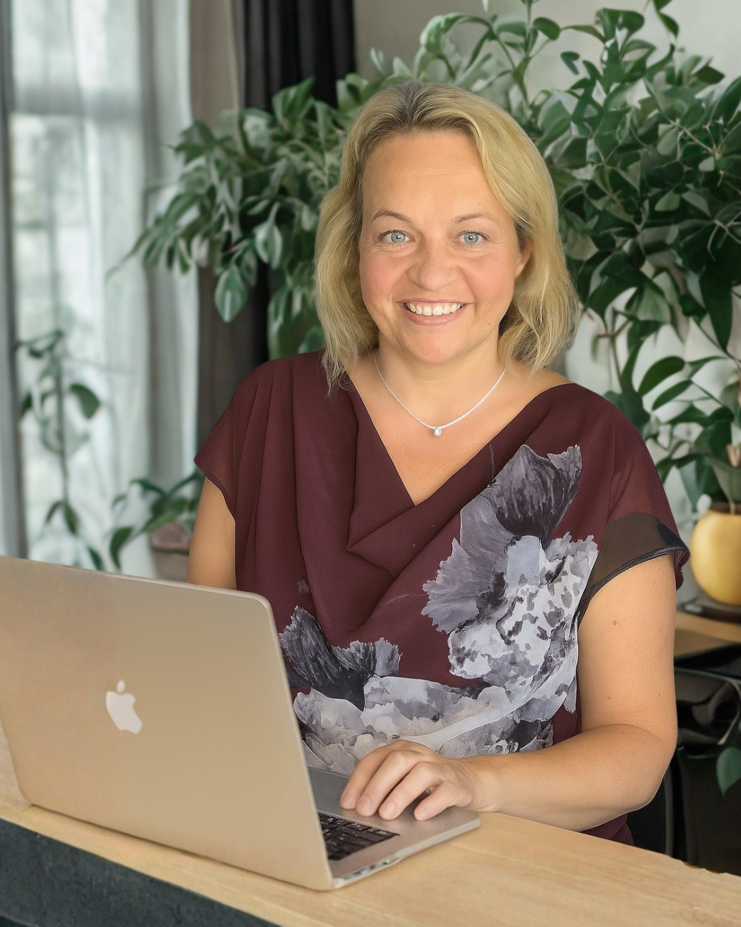 Coach Aga at a desk, working at her Apple Mac laptop
