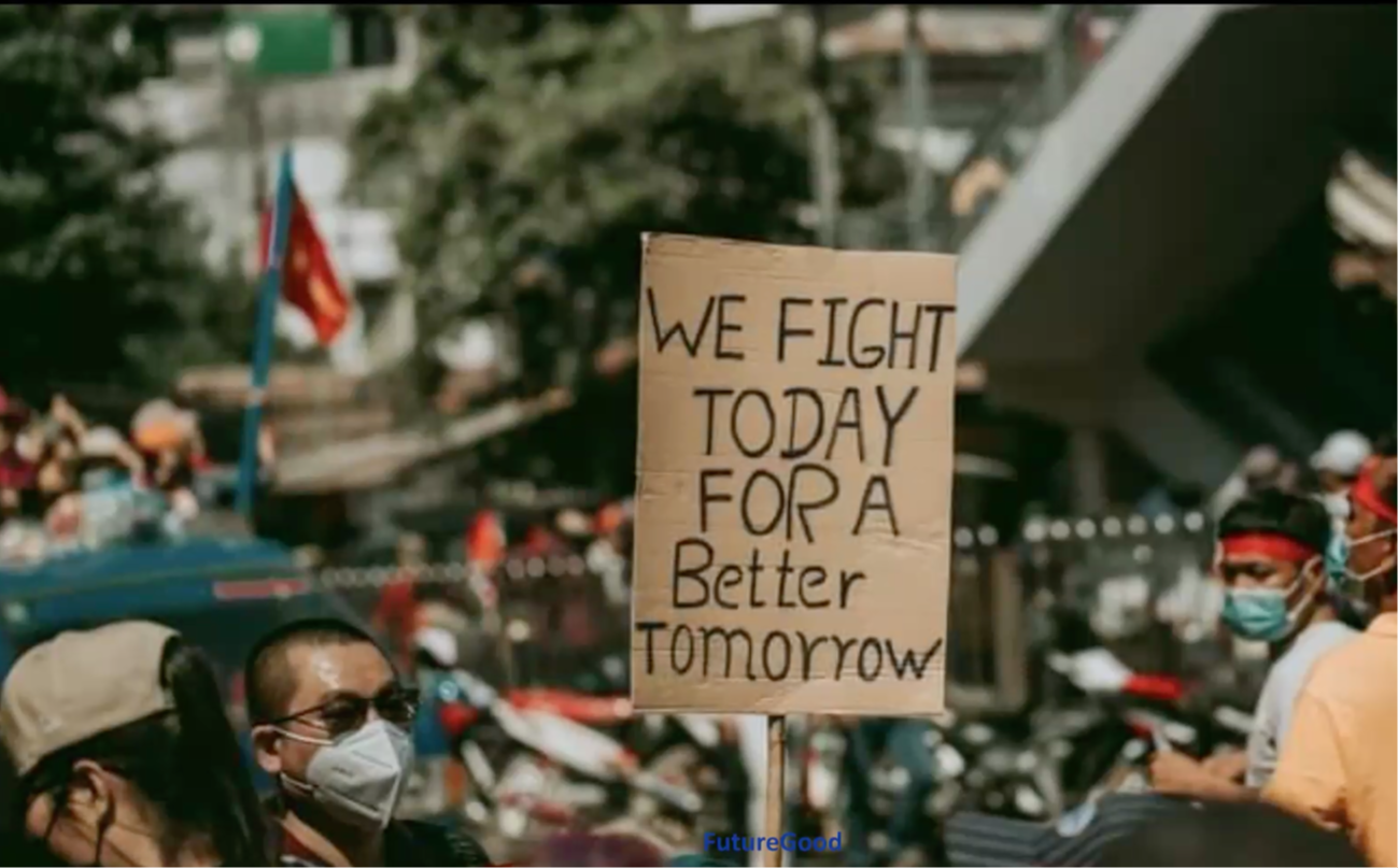 Crowd at a protest holding a handmade sign reading "We Fight Today For A Better Tomorrow," with the FutureGood logo below.