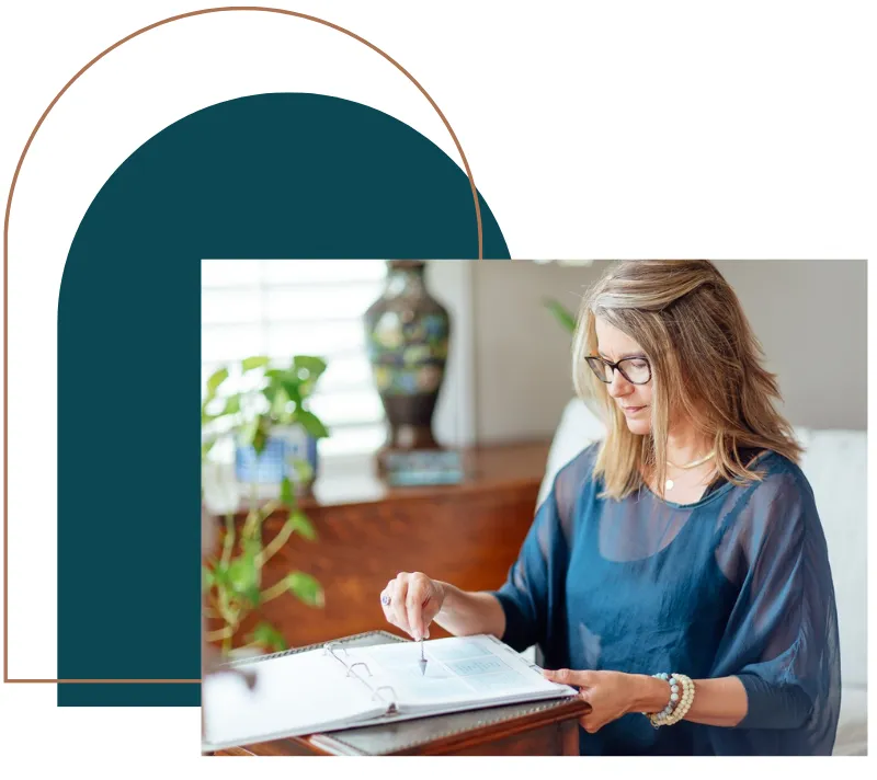 Picture of founder Tracy Southwick of MBSR(tm) Academy using a pendulum and testing charts to identify emotional stress stored in the body.