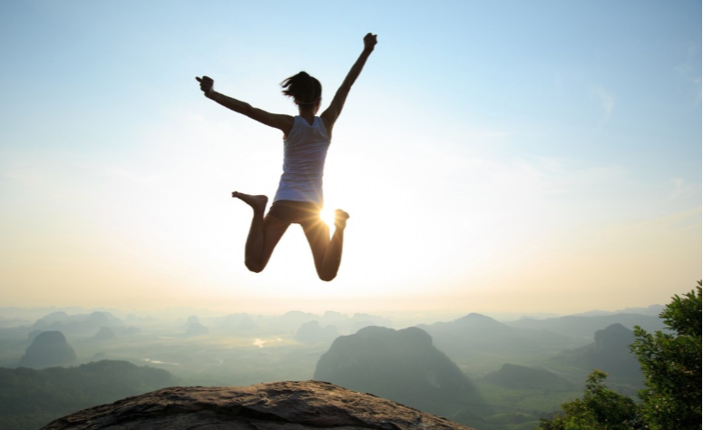 Uplifting woman jumping on mountain top