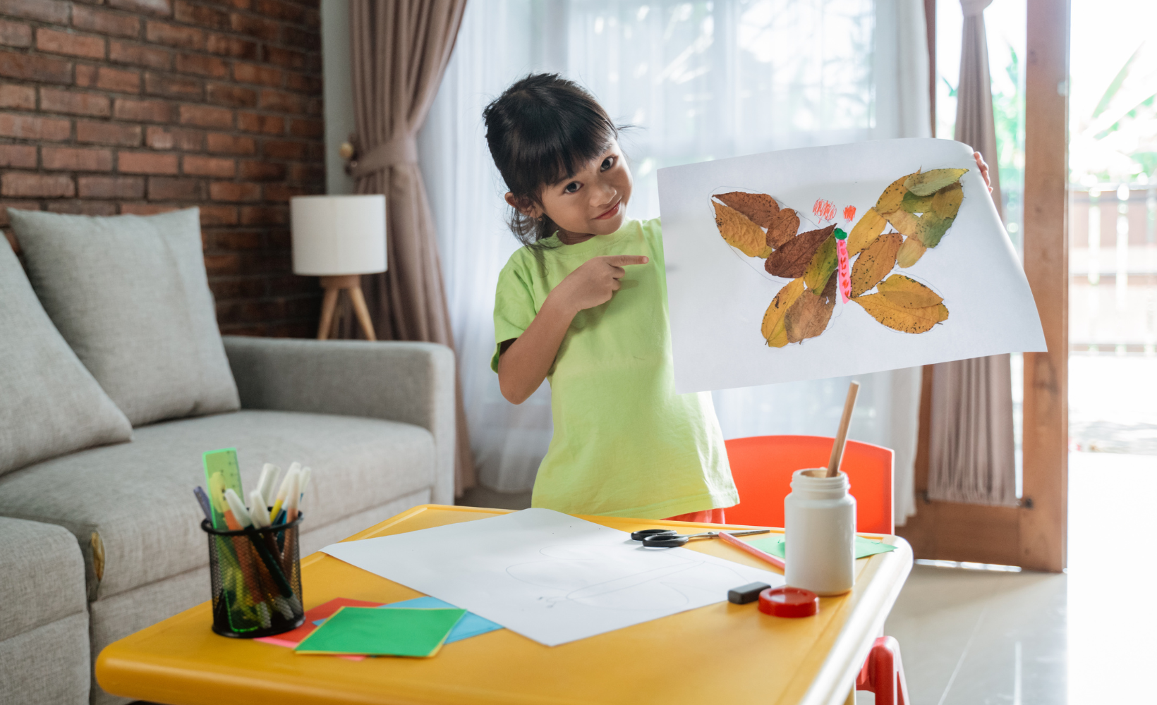 proud young child artist holding up artwork painting to show